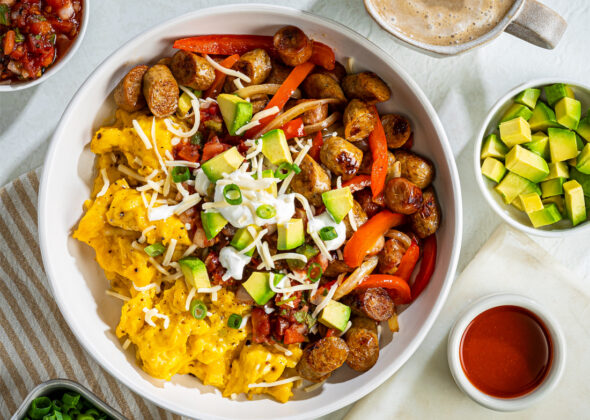 Bowl of fresh scrambled eggs, Al Fresco Breakfast sausage, and avocado on a tabletop