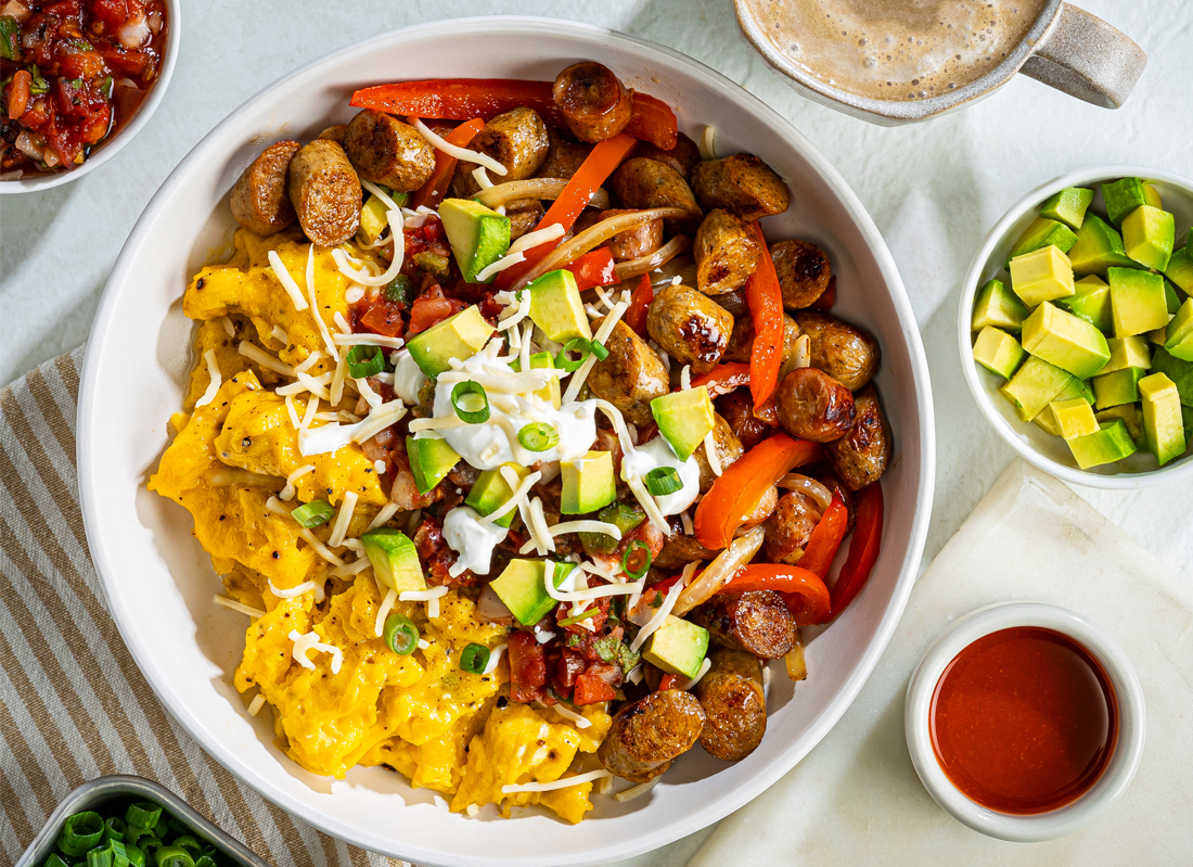 Bowl of fresh scrambled eggs, Al Fresco Breakfast sausage, and avocado on a tabletop