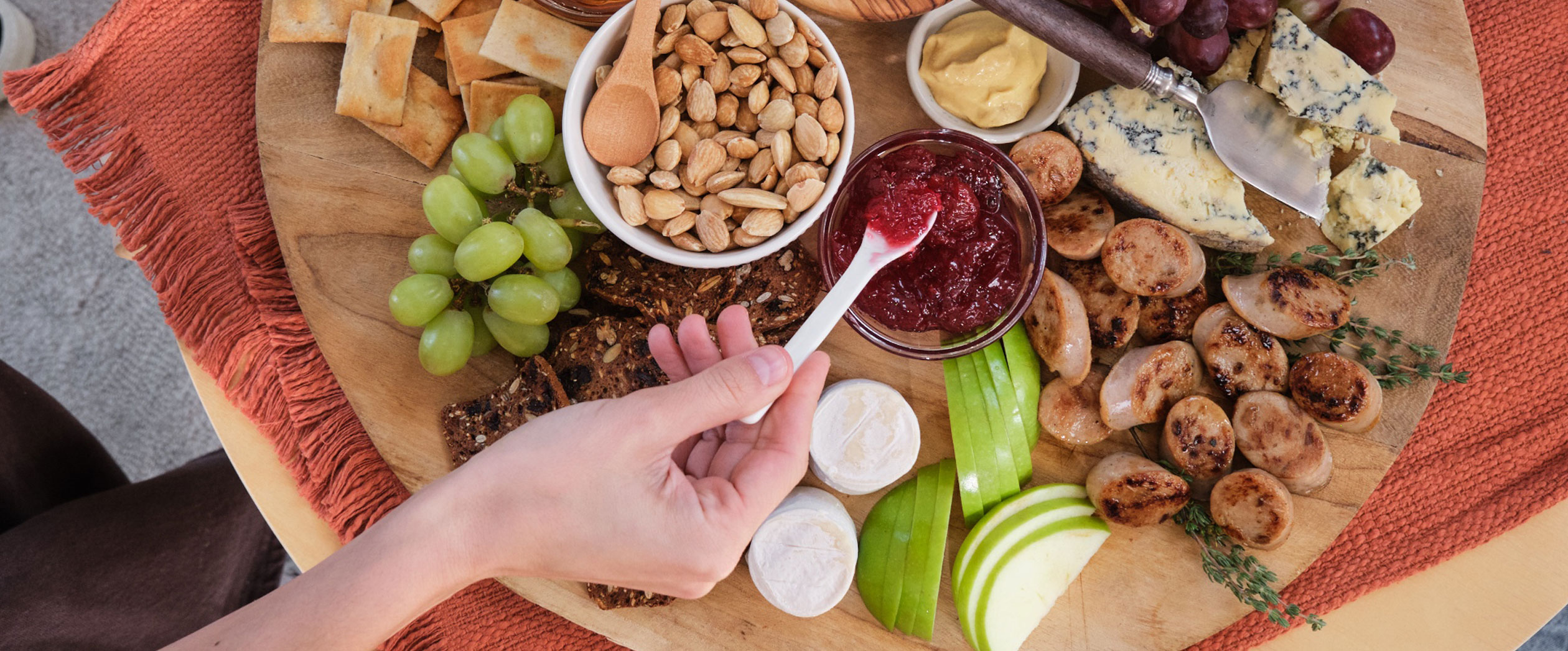 A charcuterie board featuring Al Fresco Apple Chicken Sausage and grapes, nuts, cheeses, and apple slices