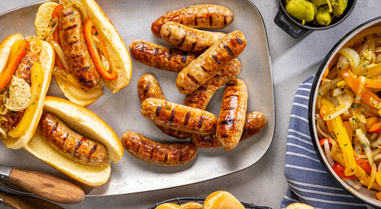 Perfectly grilled Al Fresco chicken sausage on a plate with fresh ingredients on a table