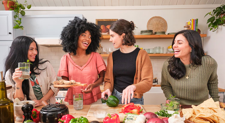 A group of friends enjoying cooking Al Fresco chicken sausage in a bright kitchen