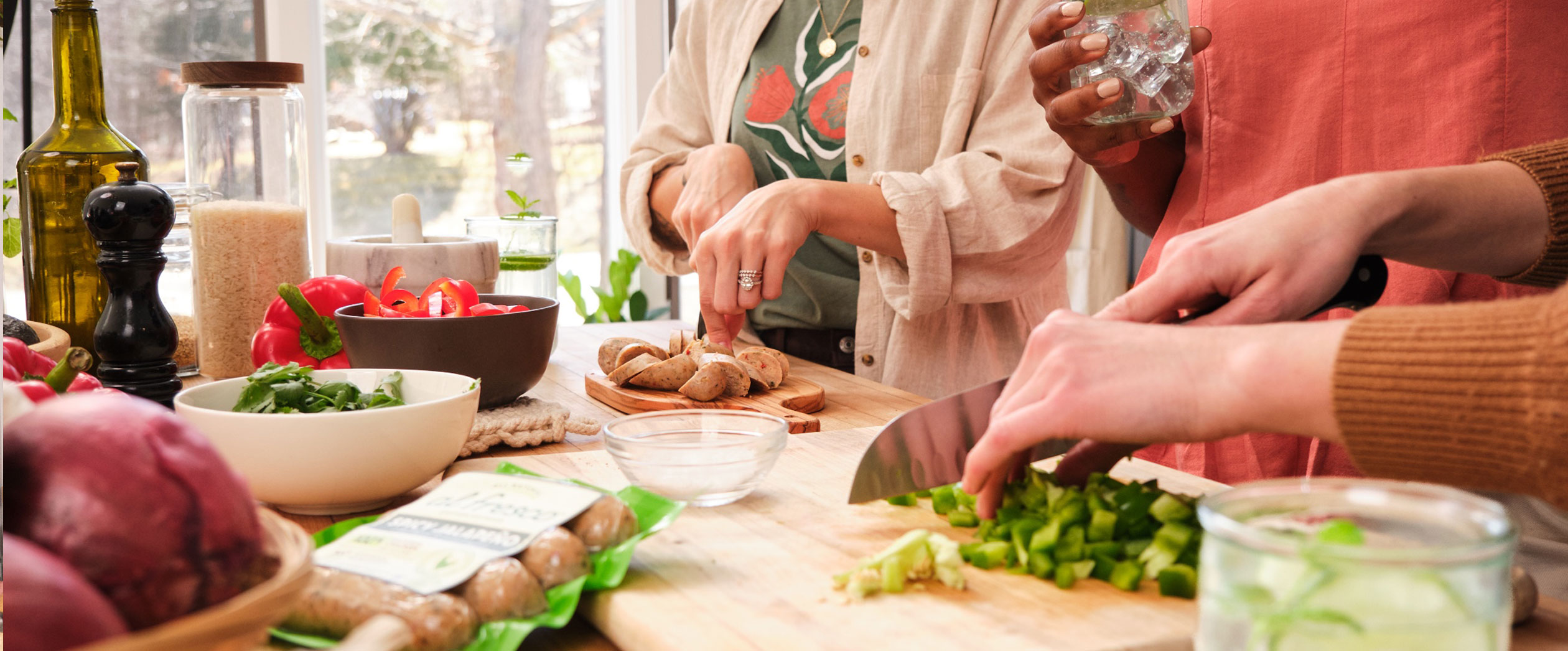 Hands chopping fresh ingredients and Al Fresco chicken sausage for a dish