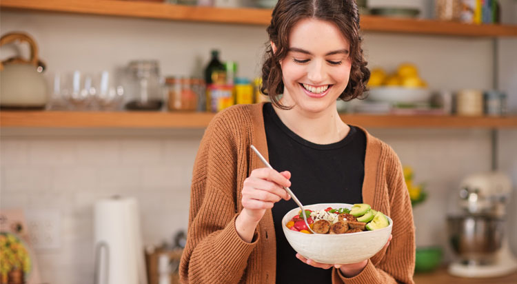 Woman enjoying a bowl that she added Al Fresco chicken sausage to