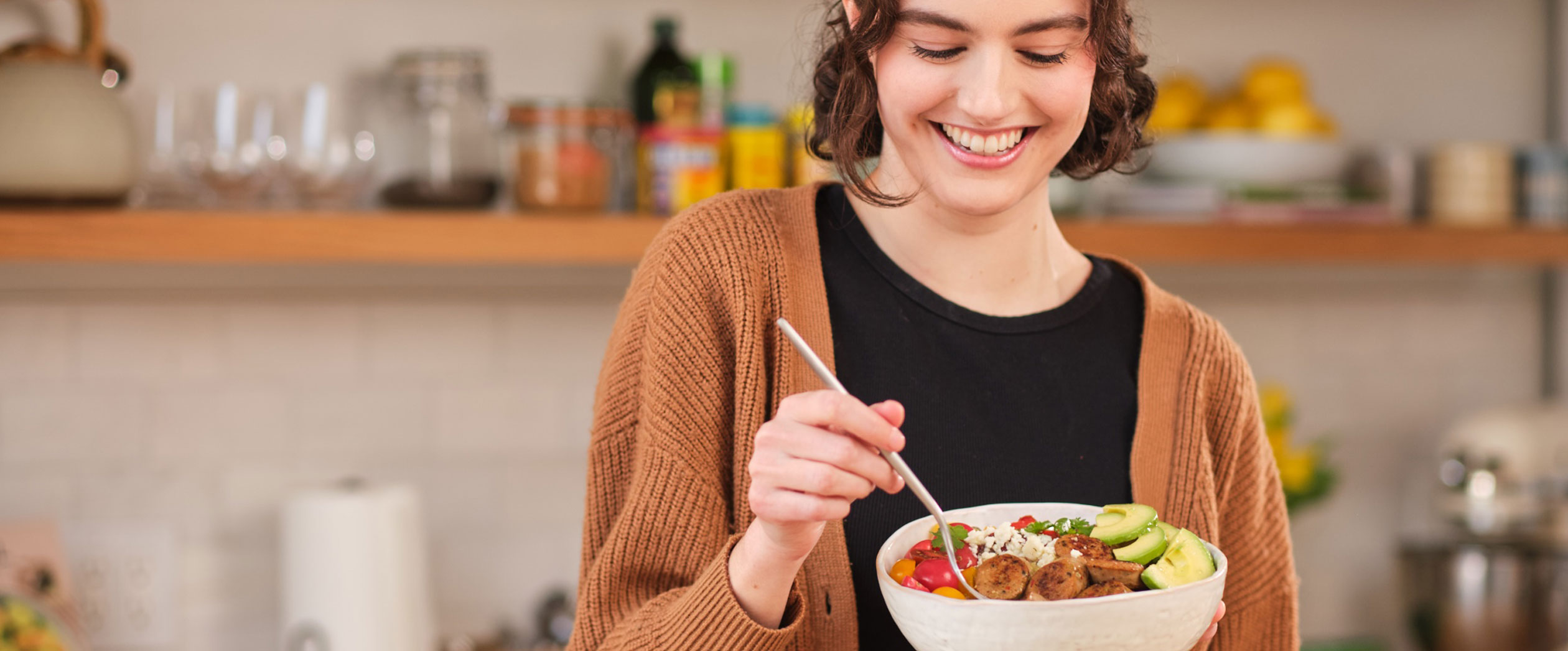 Woman enjoying a bowl that she added Al Fresco chicken sausage to