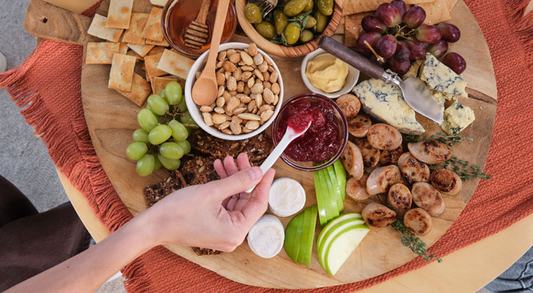 A charcuterie board featuring Al Fresco Apple Chicken Sausage and grapes, nuts, cheeses, and apple slices