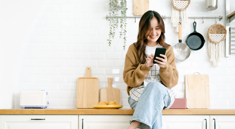 Woman in a kitchen using her phone to contact Al Fresco